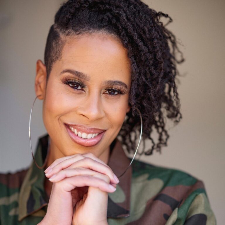 Portrait of Dominique Morisseau smiling with her hands beneath her chin.