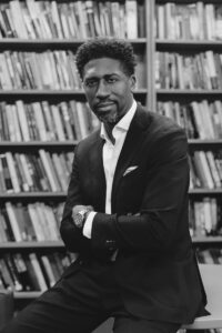 Dr. Lerone A. Martin seated in front of bookshelves.